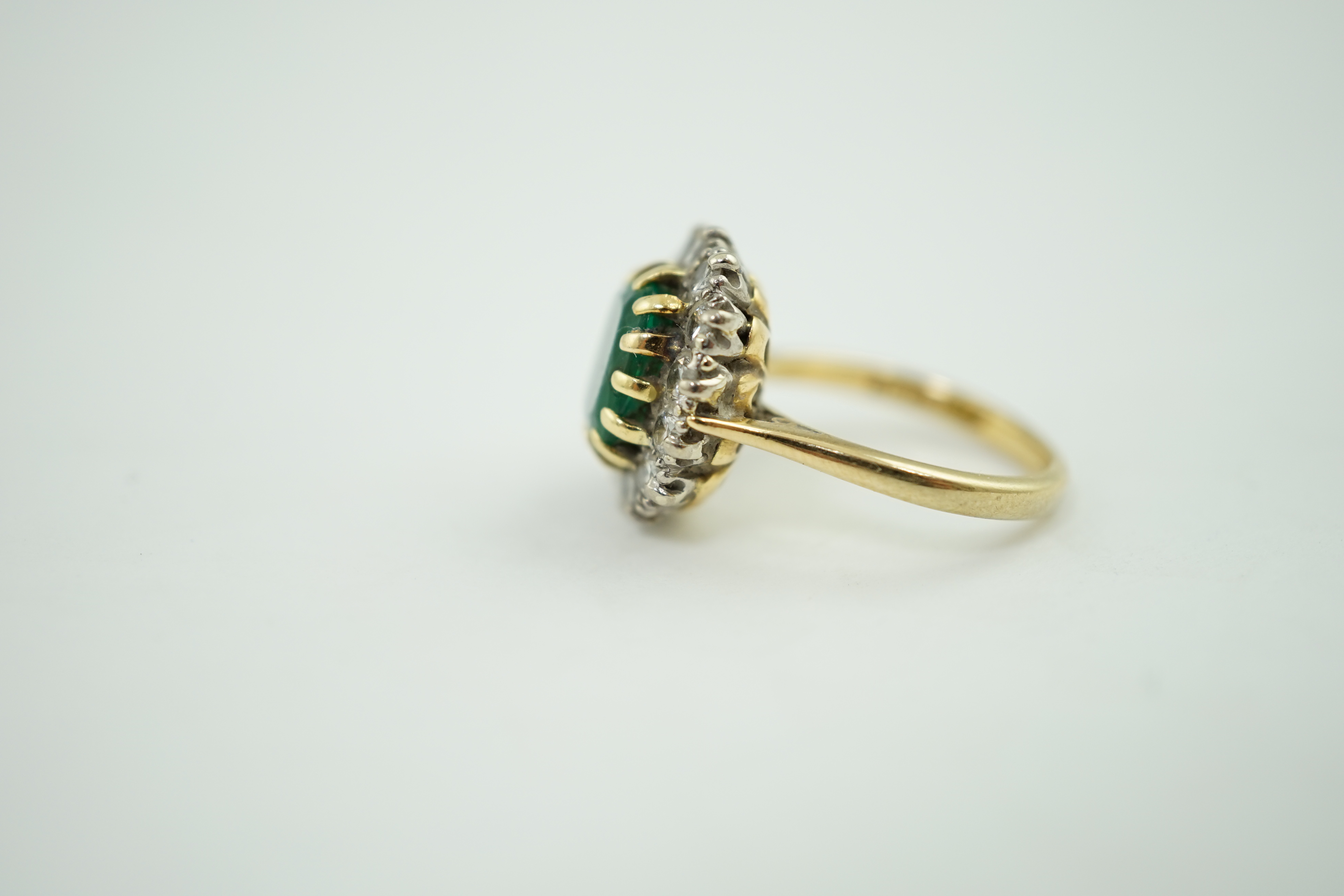 A late 1970's 18ct gold, emerald and diamond set oval cluster ring